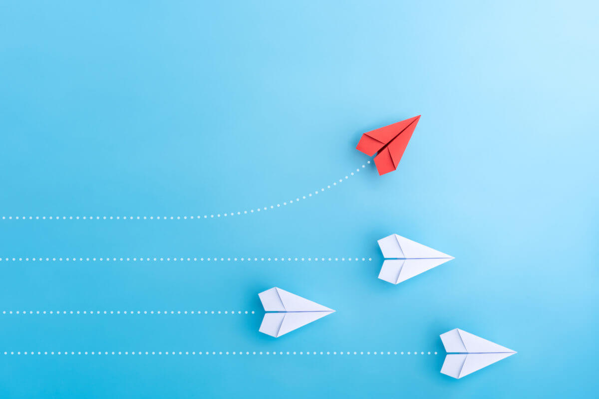 Image of one red paper airplane and three white ones