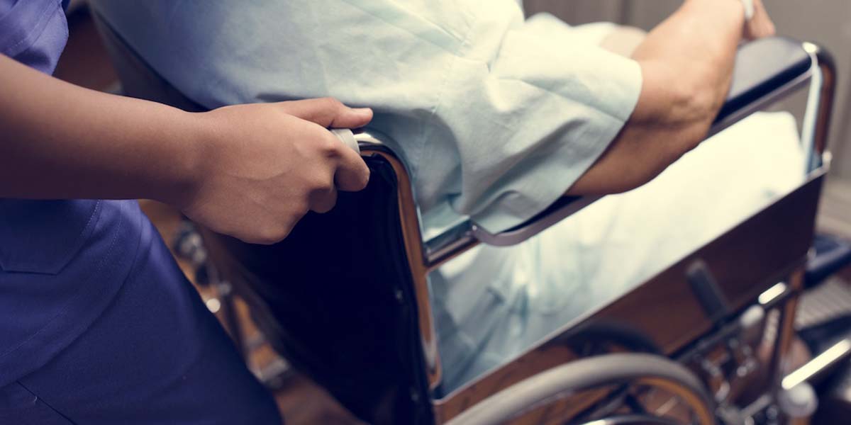 Photo of a hospital patient being transported by wheelchair