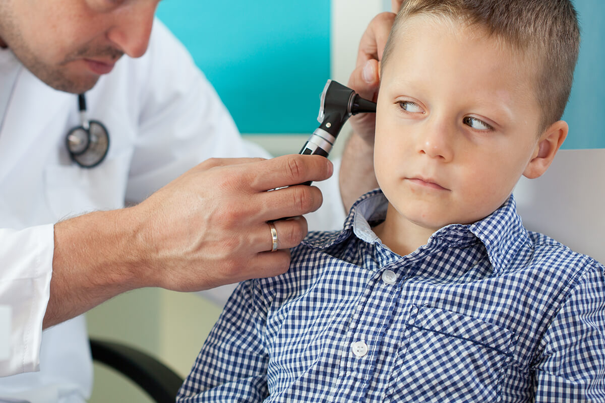 Photo of a kid in a doctor office having his ear checked