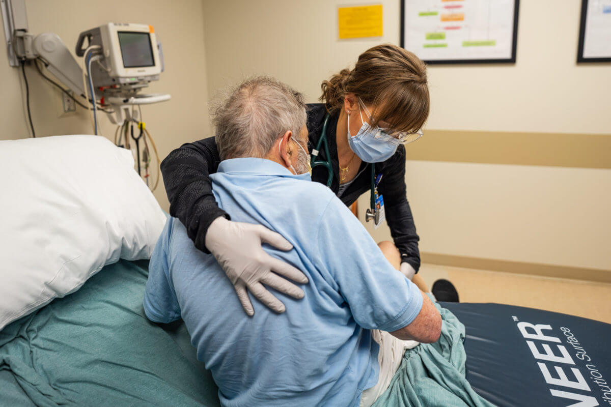 Photo of Angie Paschke, APP of Sauk Centre, helping a patient out of bed