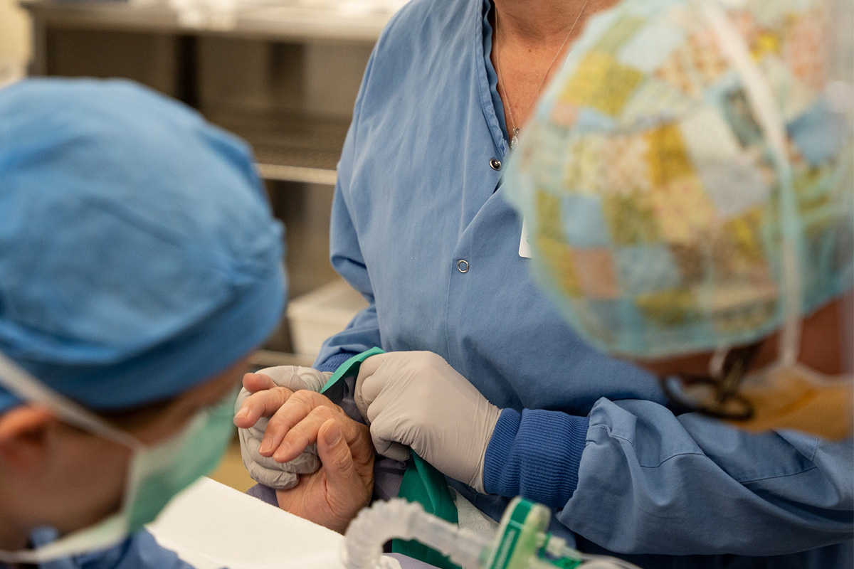Photo of a surgical nurse holding the hand of a patient