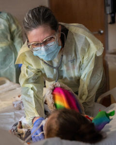 Photo of Dr. Kathy Kulus, bedside with pediatric patient
