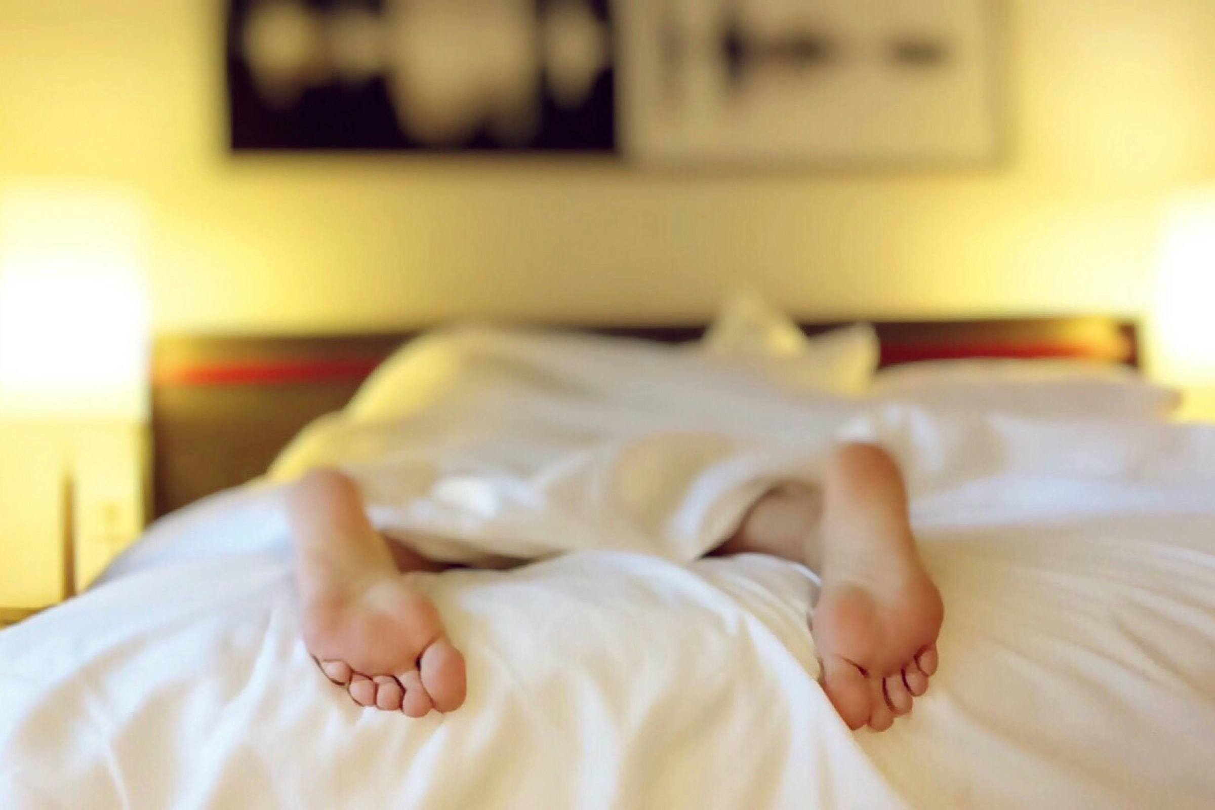 Photo of feet sticking out of a bed representing someone who can't sleep. APP CME Sleep Disorder