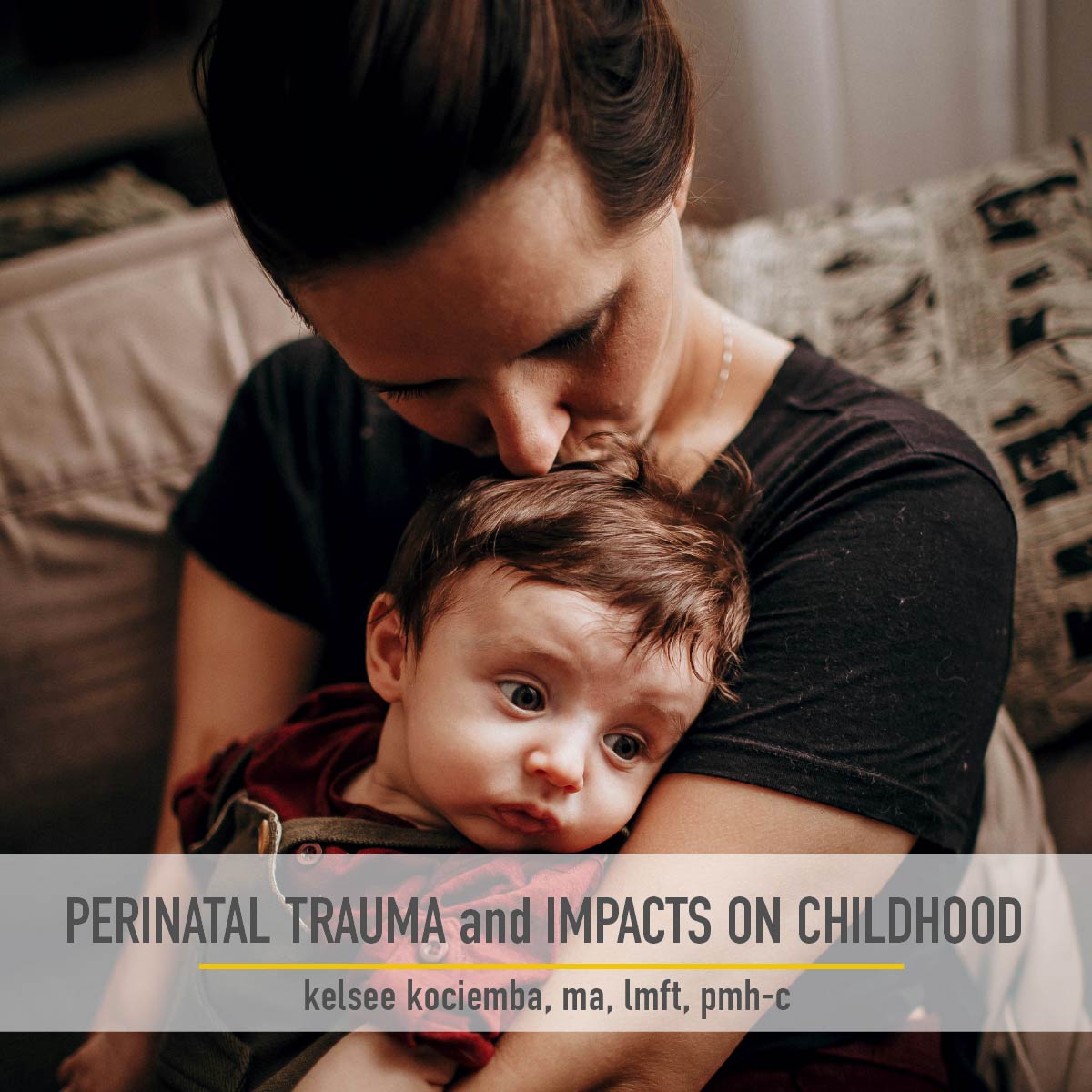 Young mother sitting on a couch holding her distraught child