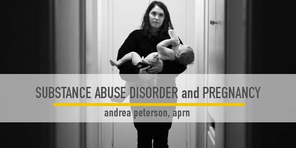 Photo of a young mother with a toddler in her arms standing in a dimly lit hallway