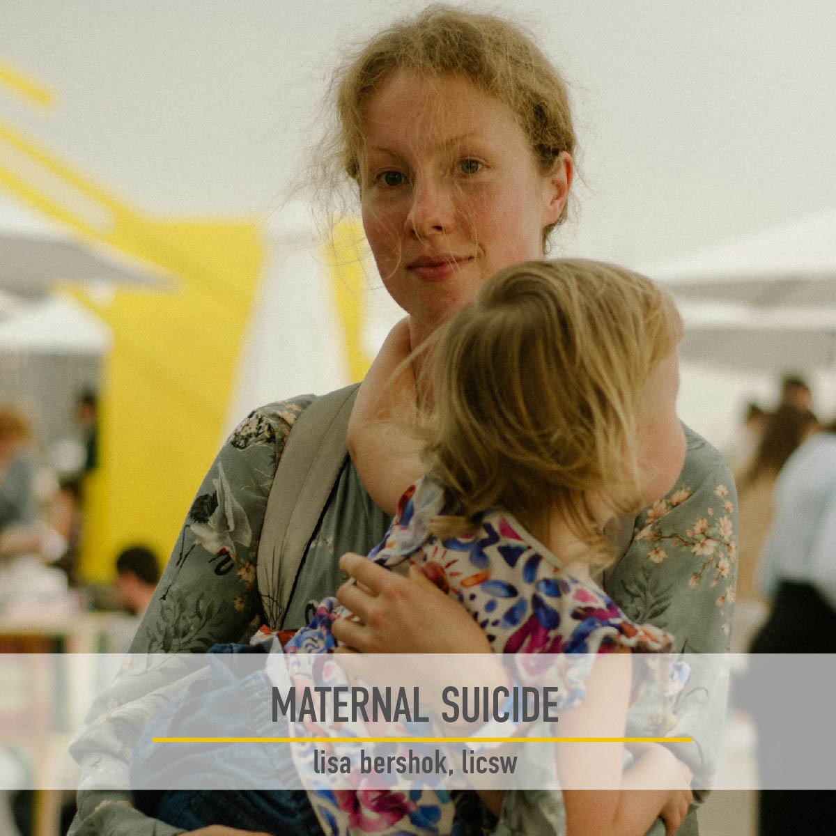A mother holding her toddler in her arms in a busy outdoor market
